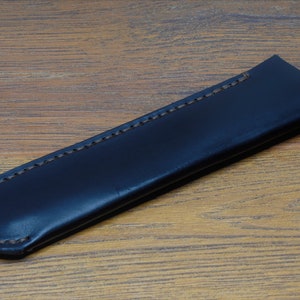 May include: A black leather pen case with brown stitching.