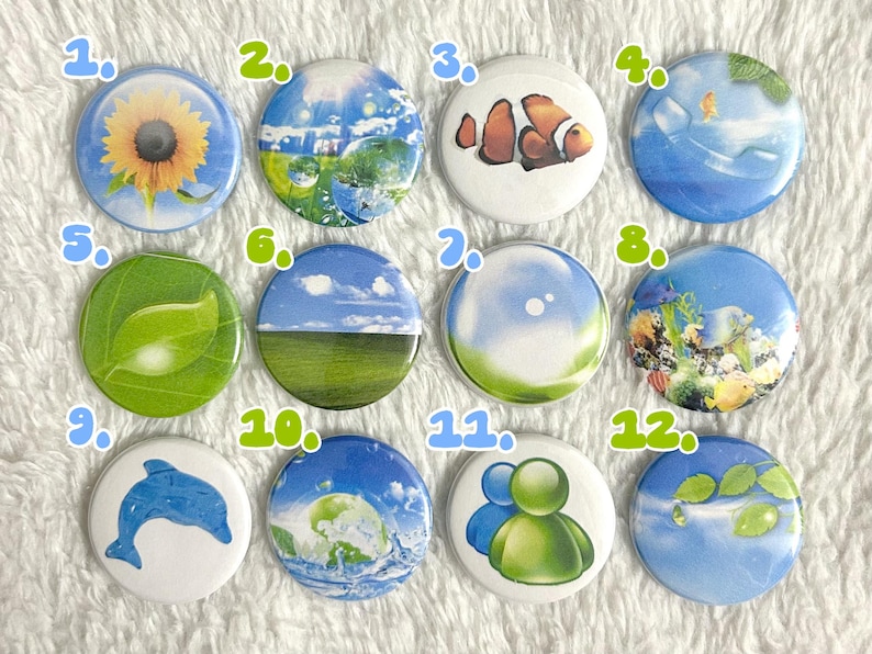 May include: A collection of twelve round pinback buttons with various nature-themed designs. The buttons feature images of a sunflower, sky, a clownfish, a dolphin, and leaves. The color palette includes blue, green, yellow, and white.