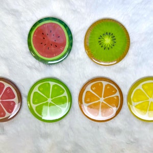 May include: Six round coasters with different fruit designs. The coasters feature a watermelon, kiwi, grapefruit, lime, orange, and lemon.