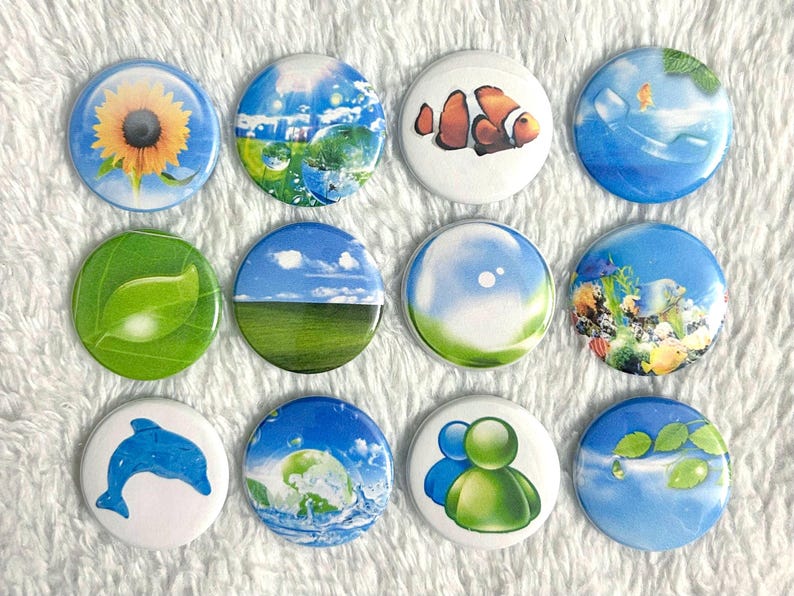 May include: A collection of twelve round pinback buttons with various nature-themed designs. The buttons feature images of a sunflower, a clownfish, a dolphin, and scenic landscapes with clouds, water, and leaves.