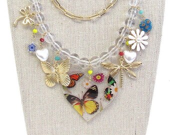 Conjunto de collar y pendientes de múltiples capas en tono dorado con dijes de flores, corazones, libélula y mariposas acrílicas gruesas, estilo cottagecore.