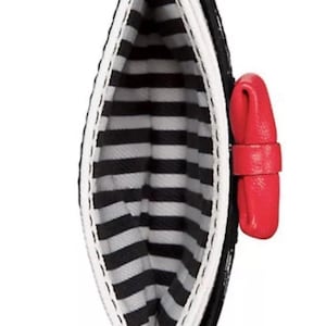 May include: Black and white striped cardholder with a red bow accent. The interior features a black and white striped pattern. The cardholder is open, showcasing the interior design. The exterior is black with a white trim.