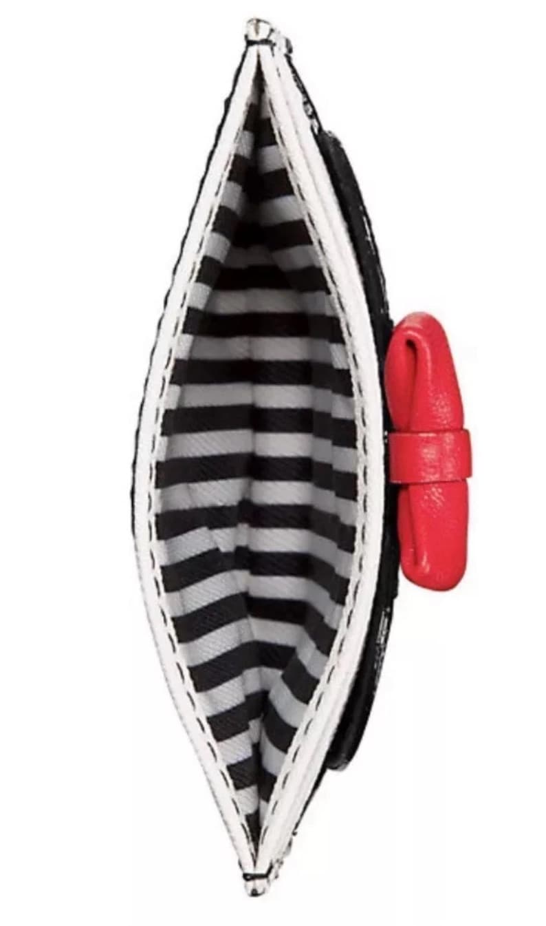 May include: Black and white striped cardholder with a red bow accent. The interior features a black and white striped pattern. The cardholder is open, showcasing the interior design. The exterior is black with a white trim.