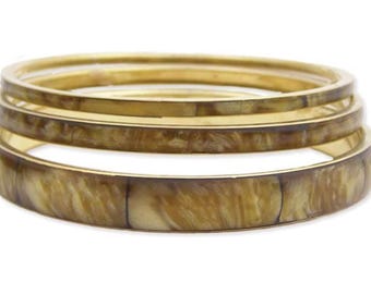 Juego de 3 pulseras apilables de resina jaspeada y metal dorado.