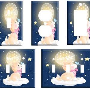 May include: A set of four light switch and outlet covers featuring a cute cartoon cat holding a balloon that says "Lovely". The background is a dark blue with white stars.