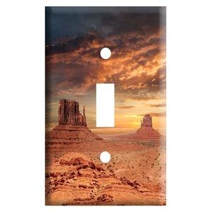May include: A light switch cover featuring a scenic landscape of red rock formations in a desert setting with a cloudy sunset sky.