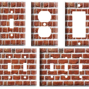 May include: Set of five light switch and outlet covers featuring a brick wall pattern. The covers are in various sizes and configurations, including single switch, double switch, and outlet.