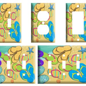 May include: A set of decorative light switch covers featuring a beach theme. The covers display colorful flip-flops, starfish, and seashells on a sandy background with a blue ocean. The set includes covers for single switches, double switches, and outlets.