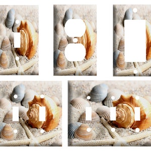May include: Set of six light switch and outlet covers featuring a beach scene with seashells and starfish on a sandy background.
