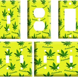 May include: Four light switch covers with a yellow background and a green marijuana leaf pattern. The text "Cannabis" is repeated throughout the pattern.