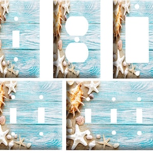 May include: Decorative light switch covers with a beach theme. The covers feature a light blue wood grain background with starfish, seashells, and sand accents. Various configurations include single and double switch plates, and outlet covers.