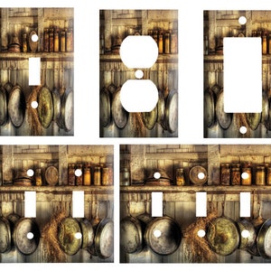 May include: Decorative light switch and outlet covers featuring a rustic kitchen scene. The design includes hanging pots and pans, shelves with jars, and a weathered wood background. The covers are available in various configurations.