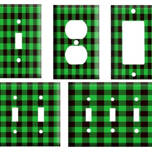 May include: Set of five light switch and outlet covers featuring a black and green buffalo plaid pattern. The covers are available in single, double, and triple switch configurations.