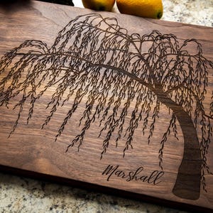 May include: A personalized walnut cutting board with a laser-etched weeping willow tree design and the name "Marshall" engraved below the tree.