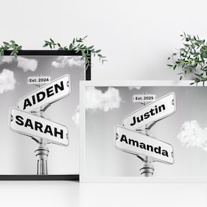 May include: Two black and white framed prints with street signs. The top sign on the left print reads "Aiden Est. 2024" and the bottom sign reads "Sarah". The top sign on the right print reads "Justin Est. 2025" and the bottom sign reads "Amanda".