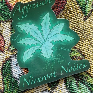 May include: A sticker with a dark green background and a stylized illustration of a plant with light blue leaves and roots. The sticker has the words "Aggressive Nirnroot Noises" in a cursive font.