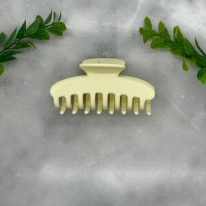 Peut inclure: Une pince &agrave; cheveux en plastique jaune clair avec une finition lisse.