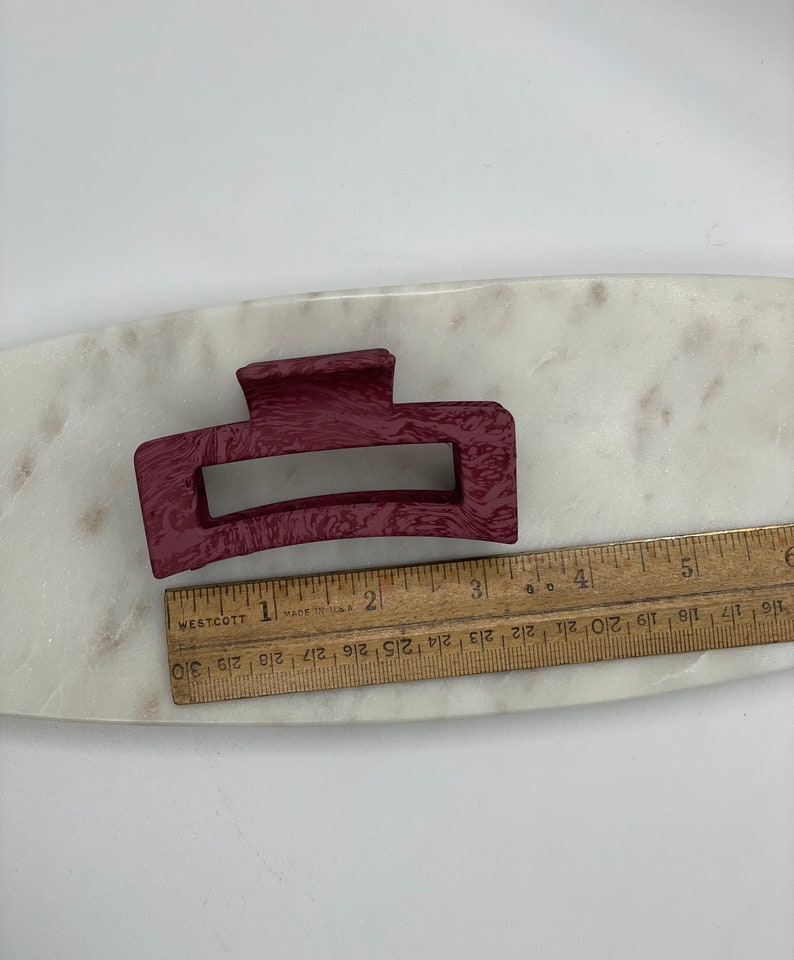 May include: A burgundy plastic hair claw clip. The clip is approximately 3 inches long.