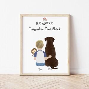 May include: A framed print with a watercolor illustration of a boy and a dog sitting back to back. The boy is holding a stuffed lion. The text reads "BE AWARE: Imagination Zone Ahead" with the names "Sam" and "Will" below the illustration.