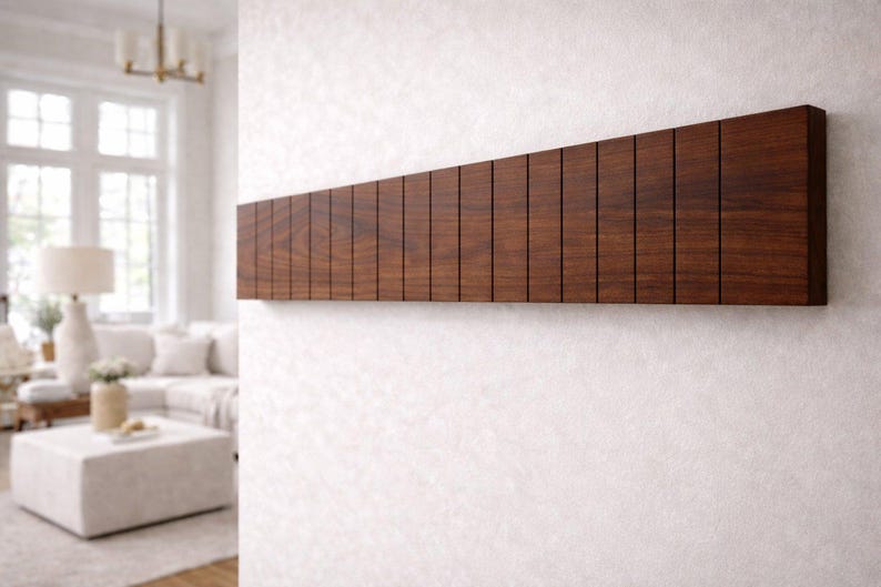 May include: A dark brown wooden wall-mounted coat rack with a series of vertical slots. The rack is rectangular and mounted on a white wall. The design is modern and minimalist, suitable for a hallway or entryway.