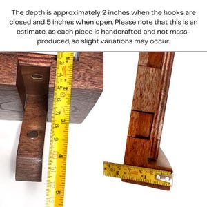 May include: Close-up of a handcrafted wooden object with a measuring tape. The depth is approximately 2 inches when closed and 5 inches when open. The wood is a rich brown color. The text in the image says, "The depth is approximately 2 inches when the hooks are closed and 5 inches when open."