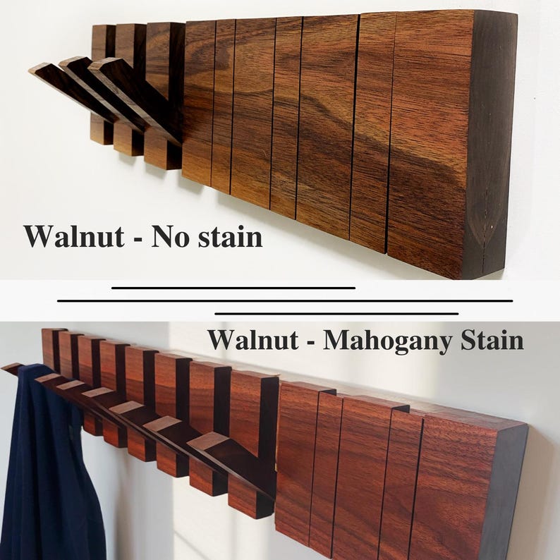 May include: Wooden wall-mounted coat rack with multiple folding hooks. The top section is walnut with no stain, and the bottom section is walnut with a mahogany stain. The text in the image reads "Walnut - No stain" and "Walnut - Mahogany Stain".