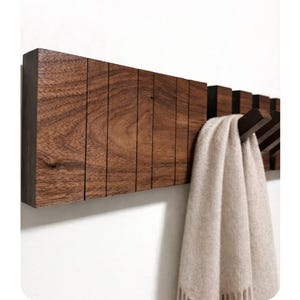 May include: A wooden entryway organizer with a series of vertical slats. The organizer has hooks for hanging items like umbrellas and bags. The text "ENTRYWAY ORGANIZER" is displayed.