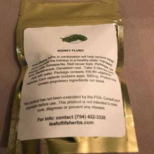 May include: A gold foil packet with a white label featuring the text "KIDNEY FLUSH" and a green leaf illustration. The label lists ingredients like stinging nettle and sarsaparilla. The packet contains 100 capsules.