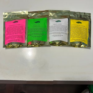 May include: Four sealed pouches with colorful labels, each containing a supplement. The labels are pink, green, white, and yellow, and feature text and a small illustration. The pouches are arranged in a row.