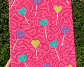 May include: A pink canvas painting with a swirling pattern of white lines. The painting features multiple heart-shaped lollipops in yellow, purple, and turquoise.