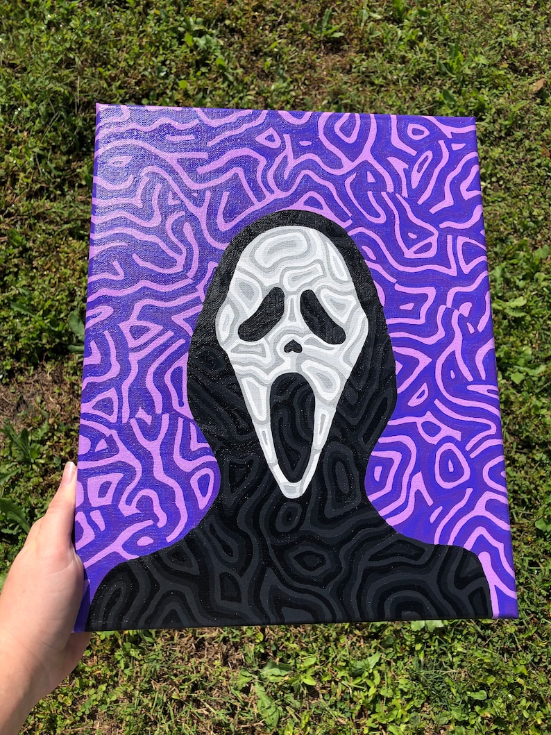 May include: A hand-painted canvas featuring a black and white illustration of the Ghostface mask from the Scream movie franchise. The background is a purple and pink abstract pattern.