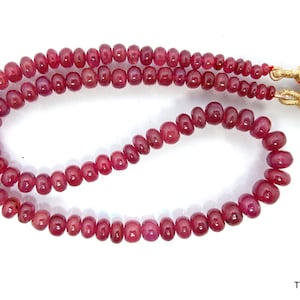 May include: A strand of deep red ruby beads with gold accents. The beads are round and smooth, and the strand is approximately 18 inches long.