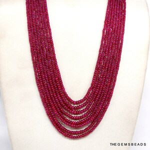 Può includere: Una lunga collana multifilo realizzata con perline di rubino rosso scuro. La collana è composta da 9 file di perline ed è lunga circa 61 cm.