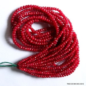 May include: A strand of red ruby gemstone beads. The beads are faceted and have a shiny finish. The beads are strung on a thin wire and are ready to be used for jewelry making.