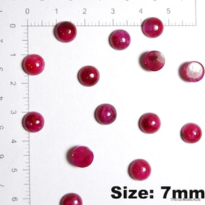 May include: A selection of polished, deep red gemstones, each about 7mm in diameter, displayed on a white background. The image includes a ruler for scale and the text "Size: 7mm".
