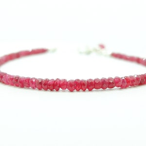 Puede incluir: Un delicado brazalete hecho con pequeñas cuentas de rubí facetadas. El brazalete está enhebrado en una cadena de plata y tiene un cierre simple.