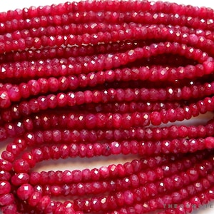 Könnte beinhalten: Eine Strähne tief roter Rubinperlen, facettiert und rund, mit hochglänzendem Finish. Die Perlen sind auf einem durchsichtigen Faden aufgefädelt und haben einen Durchmesser von etwa 4 mm.