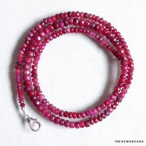Puede incluir: Una hebra de cuentas de piedras preciosas de color rojo rubí, con un cierre de plata. Las cuentas son facetadas y tienen una forma ligeramente irregular.