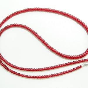 May include: A red beaded necklace with a silver clasp. The necklace is made of small, round beads that are strung together on a thin cord.