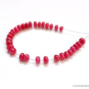 以下が含まれることがあります： 銀色のワイヤーに赤い宝石のビーズが通されたネックレス。ビーズは丸く、滑らかで磨かれた仕上げになっています。