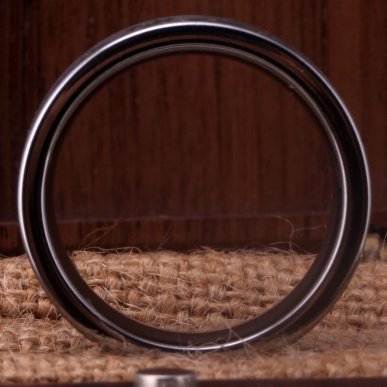 May include: A silver ring with a polished finish. The ring is thick and has a rounded edge.