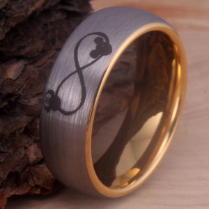 May include: A silver tungsten carbide ring with a gold band and an infinity symbol with two Mickey Mouse heads inside.