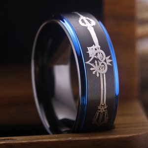 May include: A black and blue tungsten carbide ring with a silver engraved design of a keyhole and hearts.