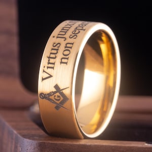 May include: A gold-colored ring with a brushed finish and an engraved inscription that reads "Virtus Junxit Non Separabit" and a Masonic symbol.