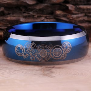 May include: A blue and silver tungsten carbide ring with a laser-etched design of the TARDIS console room from Doctor Who.