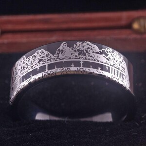 Può includere: Un anello in carburo di tungsteno nero con un'incisione argentata dell'Ultima Cena. L'anello è in stile classico.