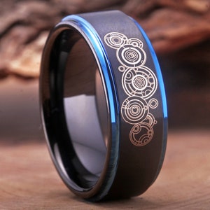 May include: A black tungsten carbide ring with a blue edge and a silver design of the TARDIS console room on the band.
