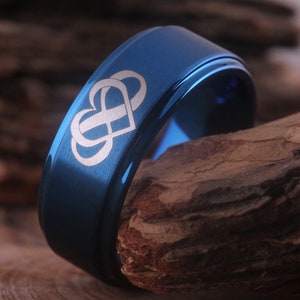 May include: A blue tungsten carbide ring with a white engraved design of two hearts intertwined with an infinity symbol.