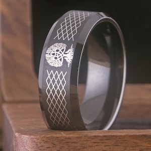 May include: Black tungsten carbide ring featuring a silver Celtic knot tree of life design and a diamond pattern on the band.