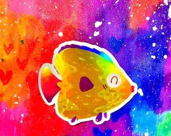 Könnte beinhalten: Ein goldener und regenbogenfarbener, schimmernder Fisch-Aufkleber mit weißem Rand und einem niedlichen Gesicht. Der Aufkleber befindet sich auf einem bunten Hintergrund mit weißen Punkten und Herzen.